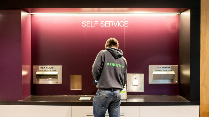 A student using the self service machines at Headington Library.
